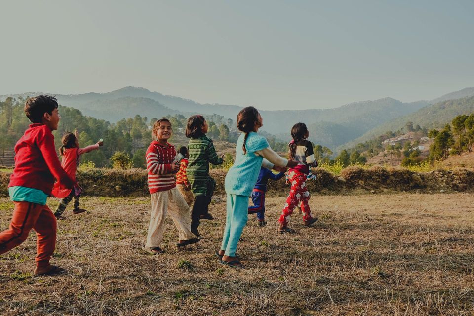 A group of children running and playing across an open field